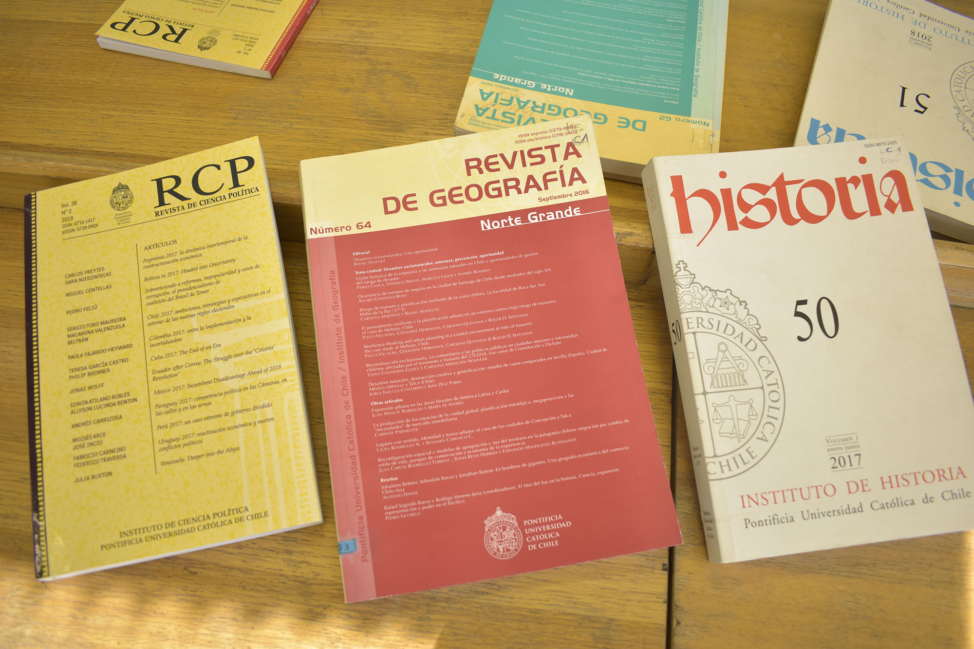 Fotografía de volúmenes antiguos impresos de las Revistas UC: Revista de Ciencia Política, Revista de Geografía y Revista Historia.